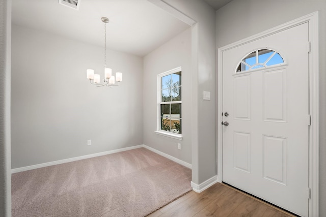 foyer entrance featuring a notable chandelier, visible vents, baseboards, and wood finished floors