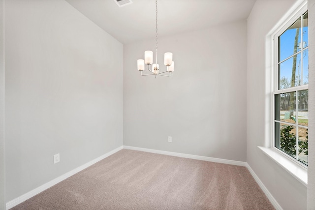 empty room featuring a notable chandelier, carpet floors, plenty of natural light, and baseboards