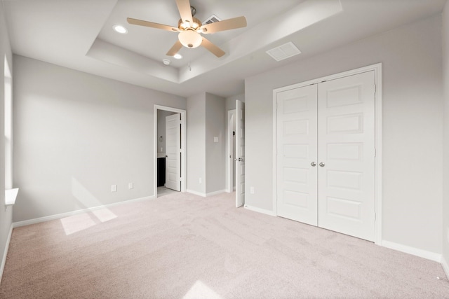 unfurnished bedroom with baseboards, a tray ceiling, carpet floors, recessed lighting, and a closet