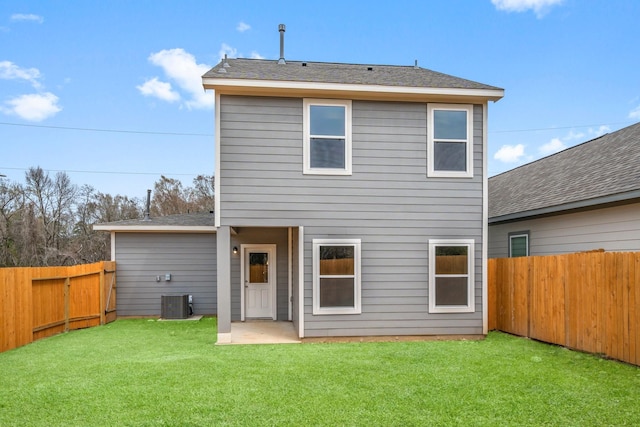 rear view of property featuring a fenced backyard, central AC, and a yard