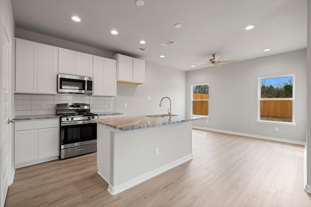 kitchen featuring light stone countertops, visible vents, a sink, stainless steel appliances, and tasteful backsplash