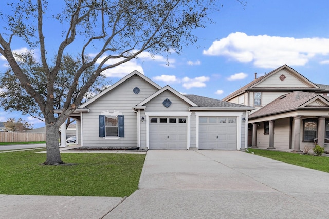 view of front of house with a front yard, concrete driveway, a garage, and roof with shingles