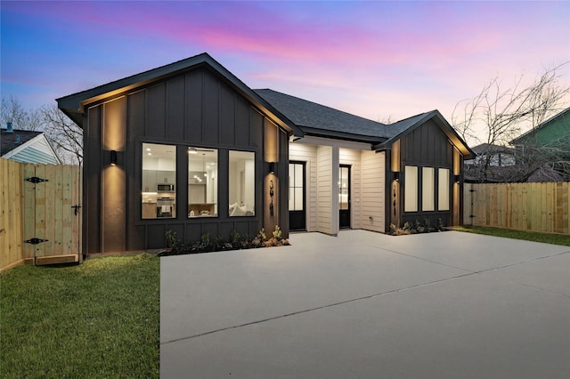 modern farmhouse featuring a gate, a yard, board and batten siding, and fence