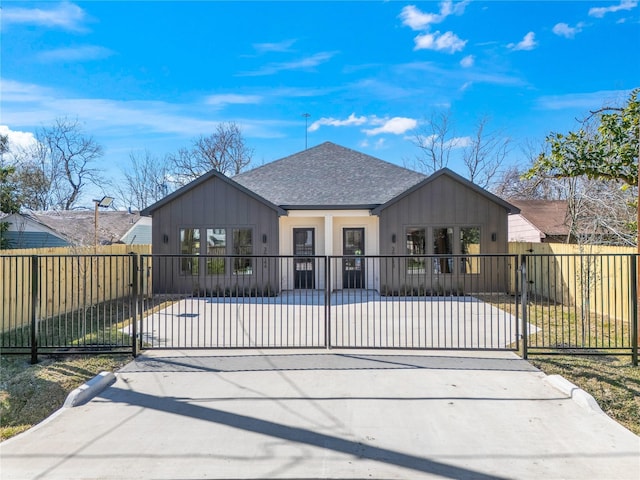 view of front facade featuring a fenced front yard, a shingled roof, and a gate