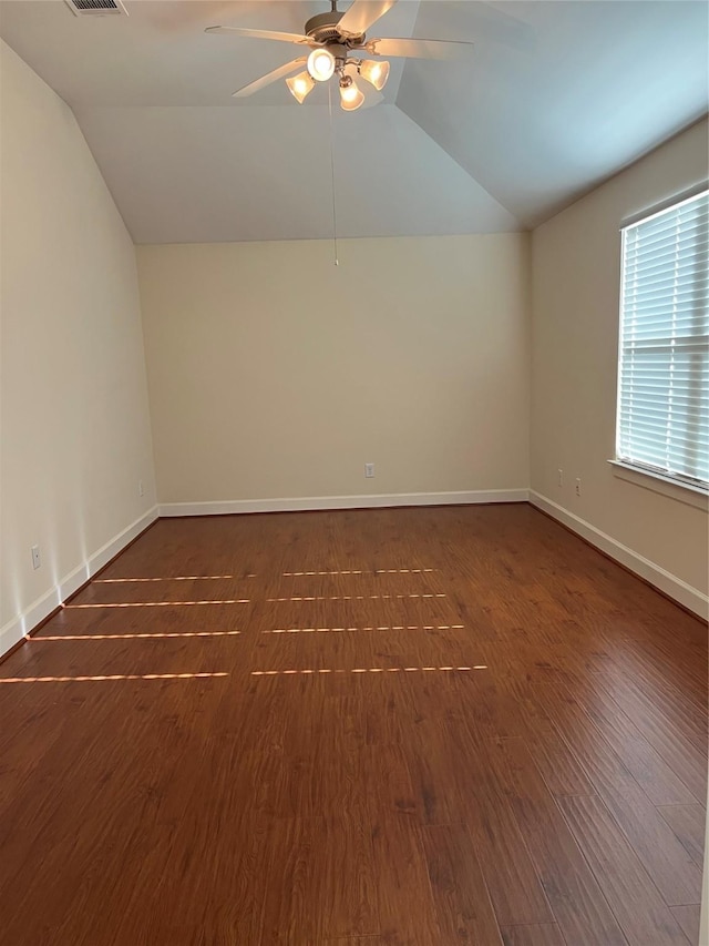 empty room featuring a ceiling fan, vaulted ceiling, baseboards, and dark wood-style flooring