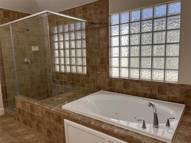 bathroom featuring tile patterned floors, a tub with jets, a healthy amount of sunlight, and a stall shower