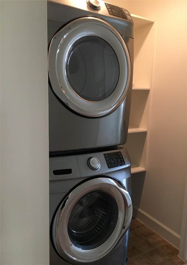 laundry room featuring tile patterned floors, stacked washing maching and dryer, and baseboards