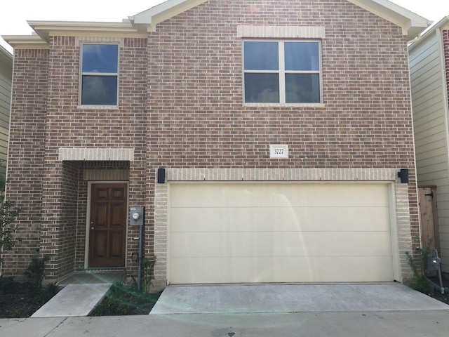 view of front of house featuring concrete driveway, an attached garage, and brick siding