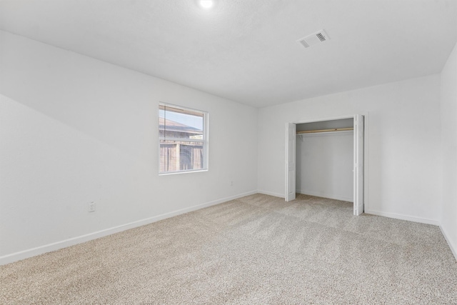 unfurnished bedroom with visible vents, light colored carpet, baseboards, and a closet