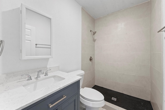 full bathroom with tiled shower, toilet, and vanity