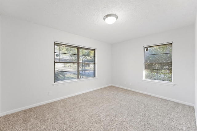 carpeted spare room with baseboards and a textured ceiling