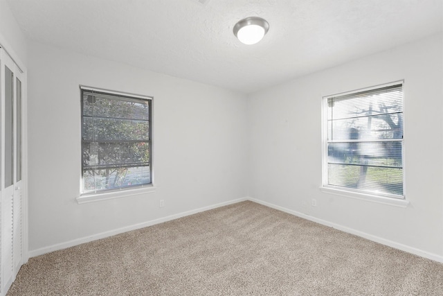unfurnished room with baseboards, a textured ceiling, and carpet flooring