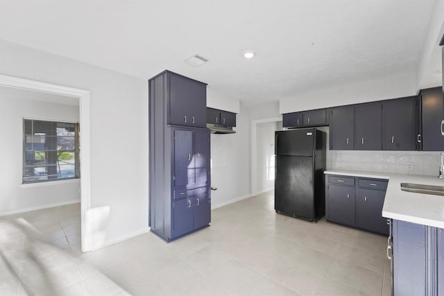 kitchen featuring visible vents, a sink, freestanding refrigerator, light countertops, and decorative backsplash