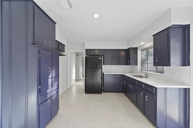 kitchen featuring visible vents, light tile patterned floors, decorative backsplash, freestanding refrigerator, and a sink