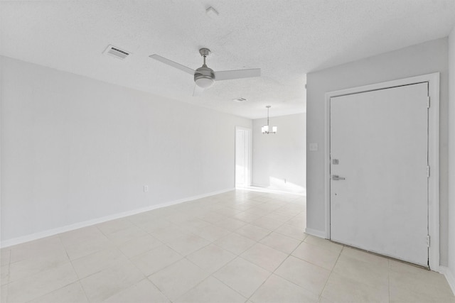empty room featuring baseboards, ceiling fan with notable chandelier, visible vents, and a textured ceiling