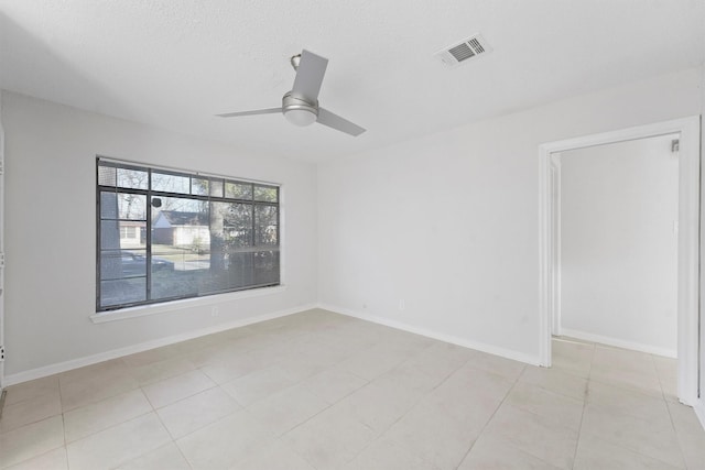 empty room featuring light tile patterned floors, visible vents, baseboards, and ceiling fan