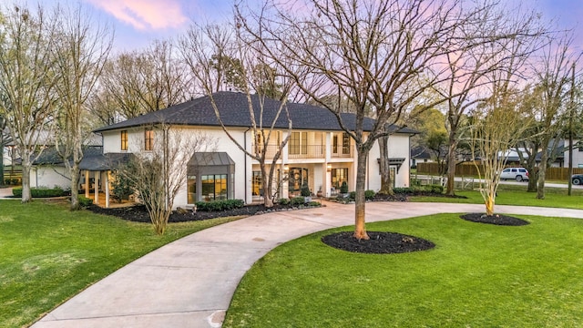 view of front of home with a front lawn, a balcony, concrete driveway, and stucco siding