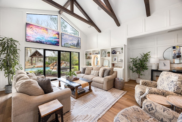 living area featuring beam ceiling, a decorative wall, high vaulted ceiling, and light wood-type flooring