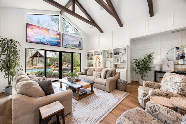living room featuring high vaulted ceiling, a decorative wall, light wood-style floors, and beamed ceiling