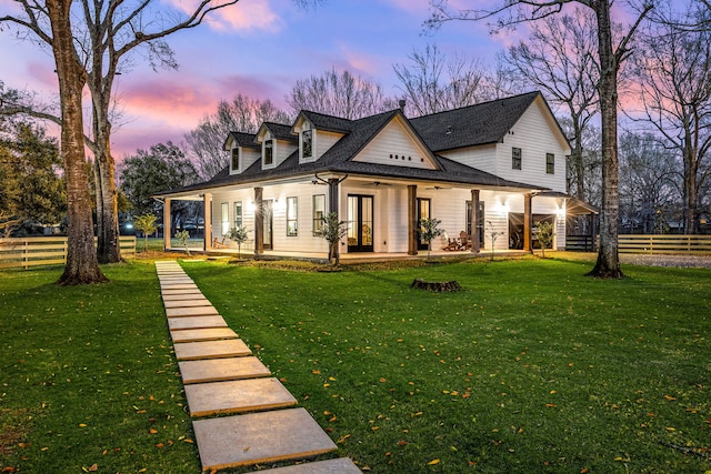 back of property at dusk with a ceiling fan, a lawn, fence, and roof with shingles