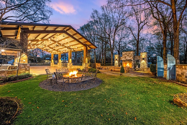 view of yard featuring a patio and an outdoor stone fireplace