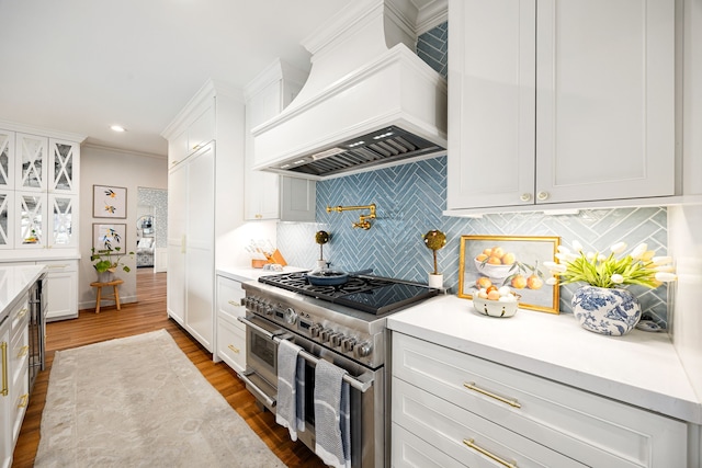 kitchen with white cabinets, dark wood-style floors, decorative backsplash, range with two ovens, and custom exhaust hood