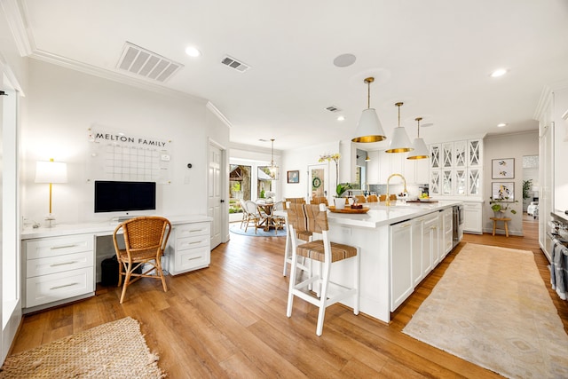 kitchen featuring light wood finished floors, visible vents, a breakfast bar area, and built in desk