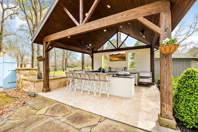 view of patio with a ceiling fan, outdoor wet bar, exterior kitchen, and fence