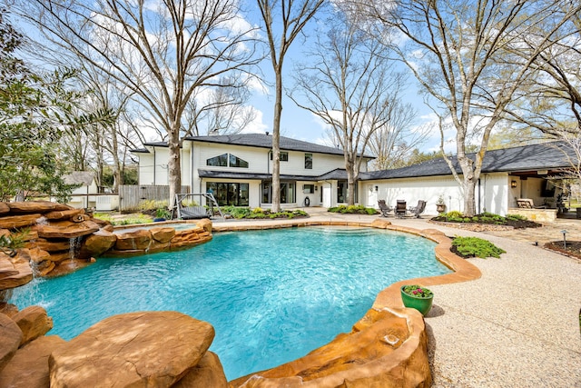 view of pool featuring a pool with connected hot tub, a patio, and fence