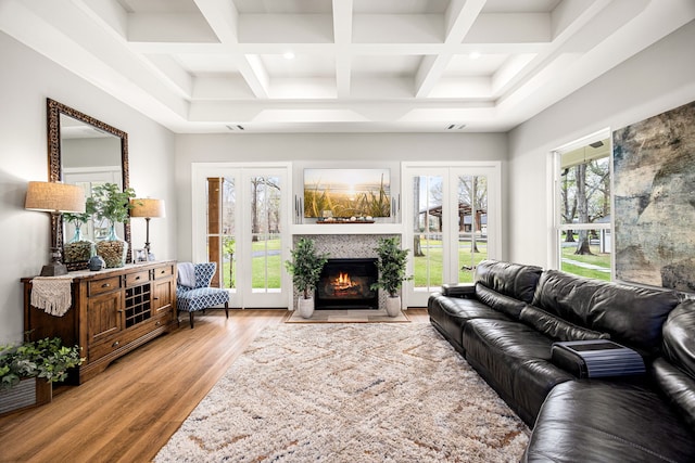 living room with light wood-type flooring, beam ceiling, coffered ceiling, and a fireplace with flush hearth