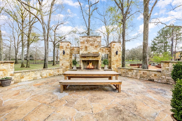 view of patio with an outdoor stone fireplace and fence