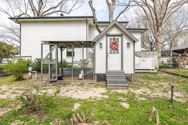 view of front facade featuring fence, entry steps, brick siding, and board and batten siding