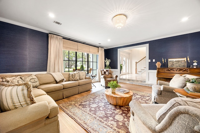 living area with stairs, crown molding, light wood-style floors, and visible vents