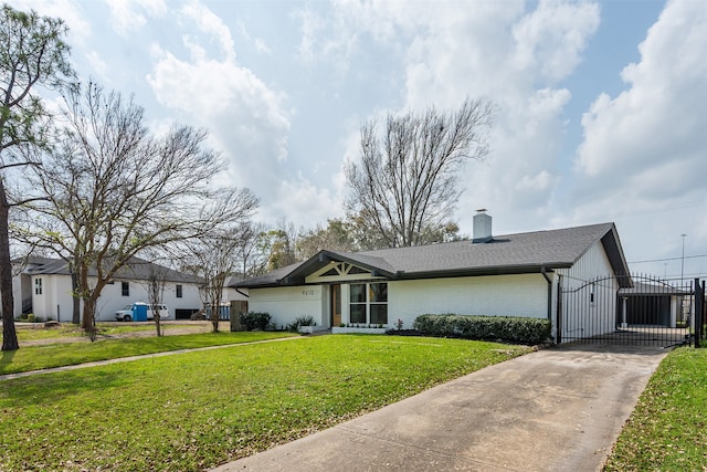 view of front of house with a gate, roof with shingles, a front yard, brick siding, and a chimney