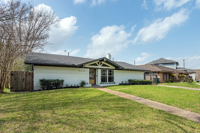 view of front of home with a front lawn, fence, brick siding, and a chimney