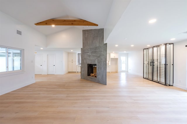 unfurnished living room with plenty of natural light, a fireplace, visible vents, and light wood finished floors