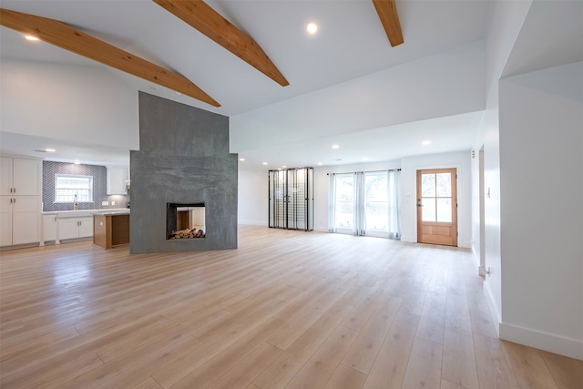 unfurnished living room with beamed ceiling, high vaulted ceiling, light wood-style flooring, baseboards, and a multi sided fireplace