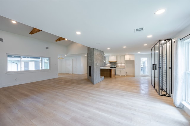 unfurnished living room with recessed lighting, light wood-type flooring, and visible vents