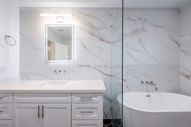 bathroom featuring vanity, tile walls, visible vents, and a freestanding bath