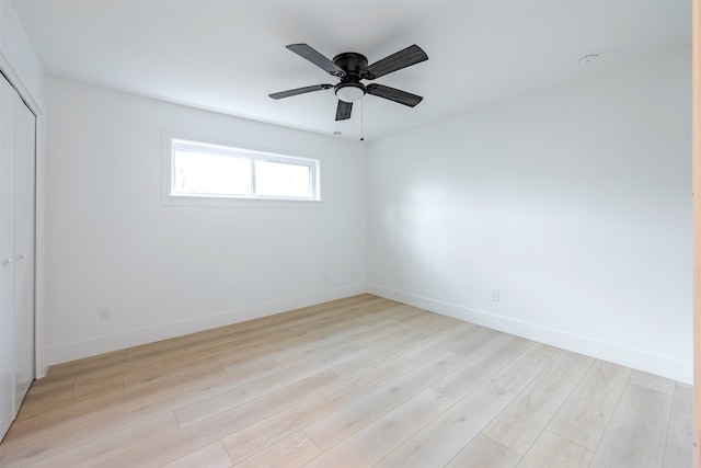 empty room featuring a ceiling fan, baseboards, and light wood finished floors