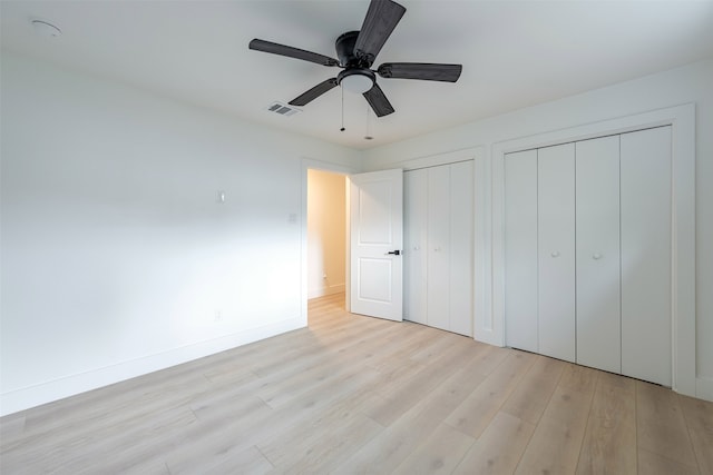 unfurnished bedroom with visible vents, multiple closets, light wood-style flooring, a ceiling fan, and baseboards