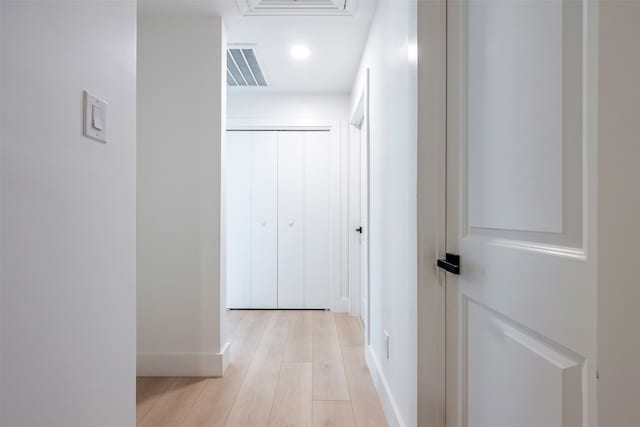 hall featuring light wood-style floors, visible vents, and baseboards