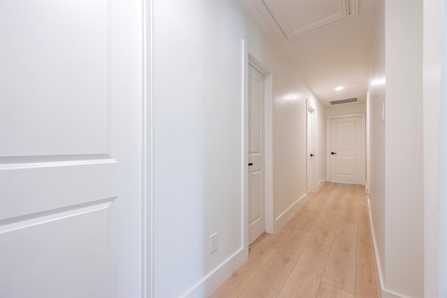 corridor featuring visible vents, baseboards, and light wood finished floors