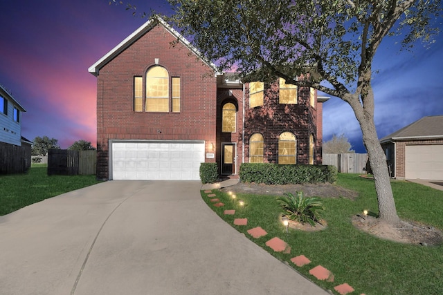 traditional-style home featuring fence, concrete driveway, a front yard, a garage, and brick siding