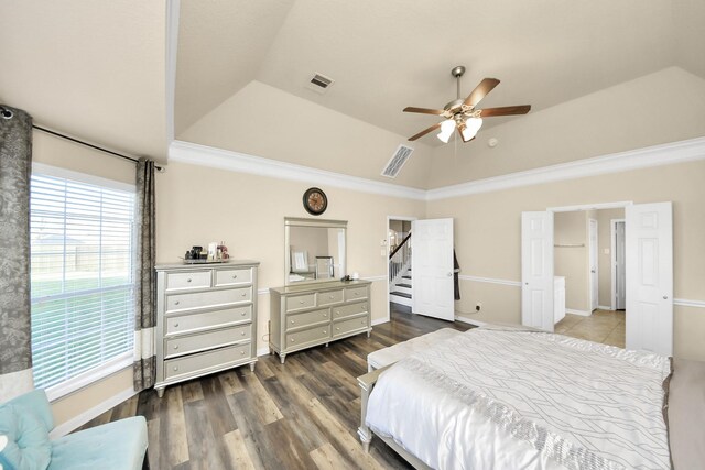 bedroom featuring a raised ceiling, wood finished floors, visible vents, and vaulted ceiling