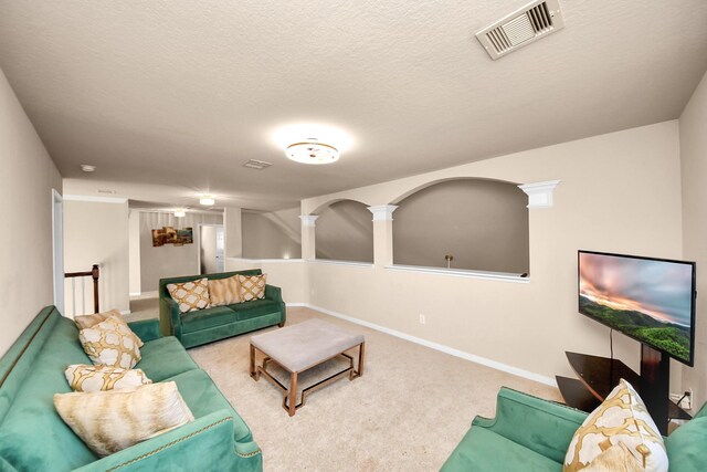 living room with visible vents, baseboards, carpet, a textured ceiling, and ornate columns