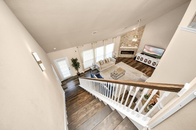 staircase with visible vents, lofted ceiling, wood finished floors, and a fireplace