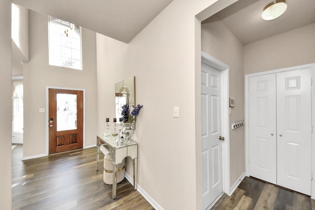 foyer entrance with baseboards, a high ceiling, and wood finished floors