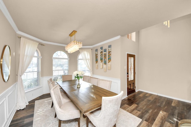 dining room featuring a wainscoted wall, dark wood-type flooring, a chandelier, and ornamental molding