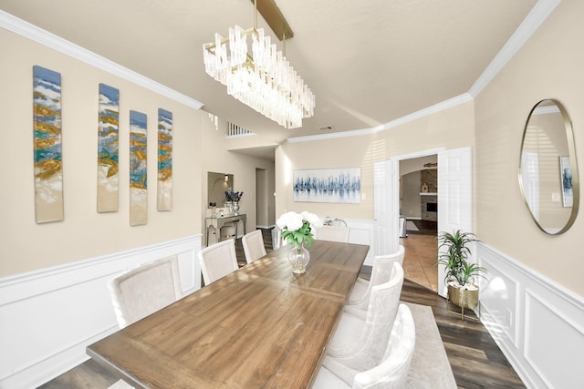 dining area featuring visible vents, a wainscoted wall, dark wood-style flooring, ornamental molding, and a notable chandelier